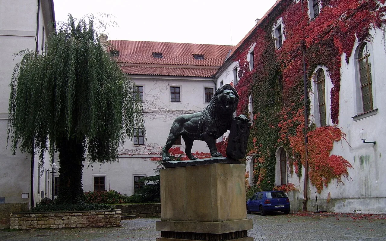 A lion statue in the courtyard of Strahov Monastery, with the abbey buildings behind